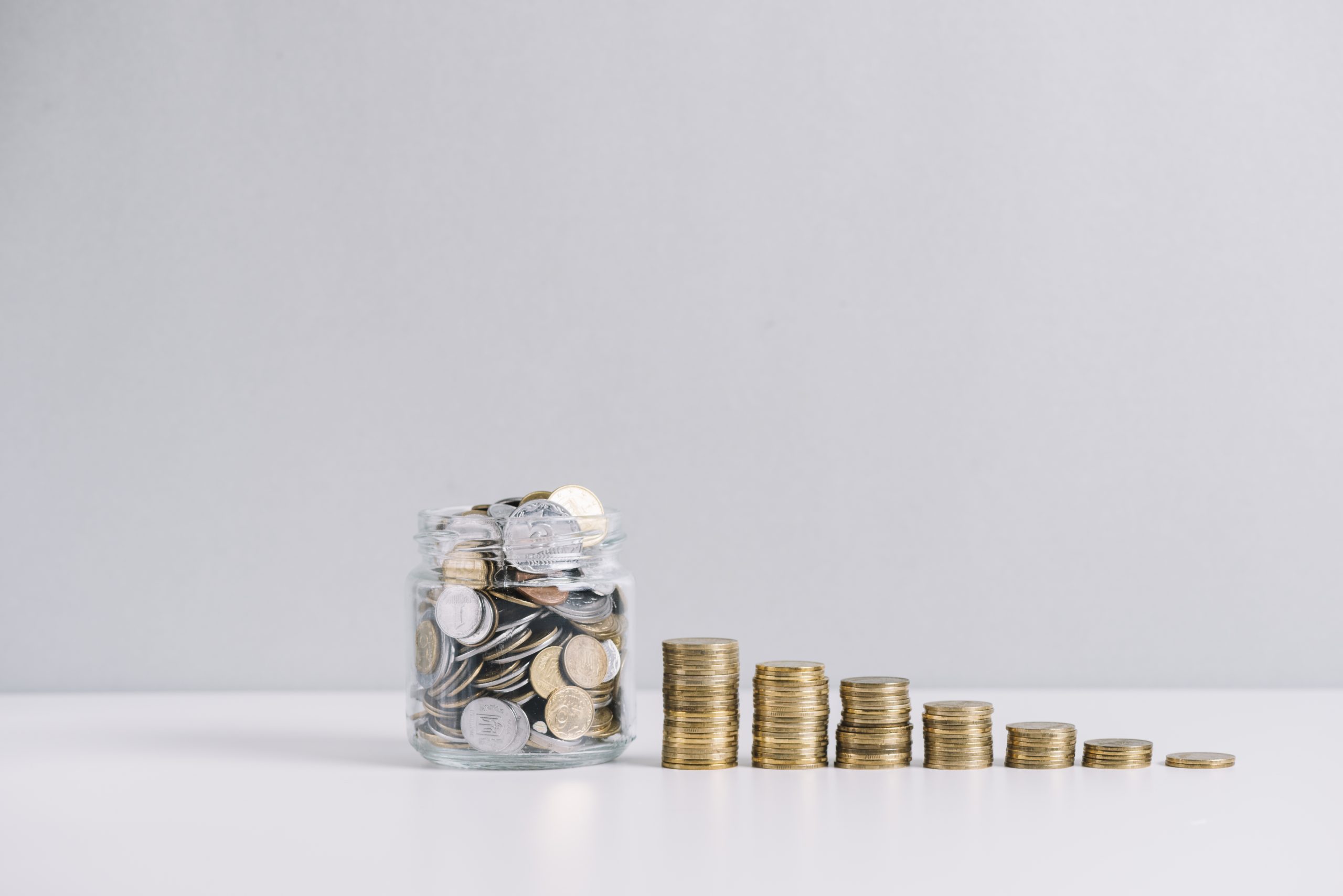 Glass Jar Full Money Front Decreasing Stacked Coins Against White Background - JB Contabilidade - IR2021: 6 mudanças que você precisa saber