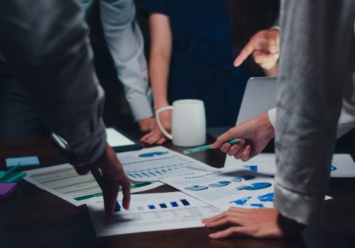 Millennial Asia businessmen and businesswomen meeting brainstorming ideas about new paperwork project colleagues working together planning success strategy enjoy teamwork in small modern night office.